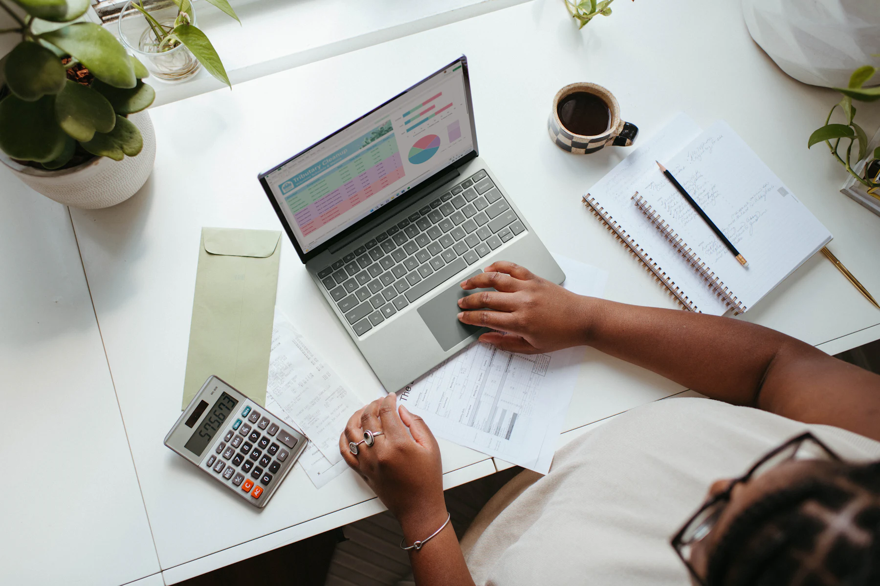Overhead view of a person reviewing finances on a laptop with a calculator
