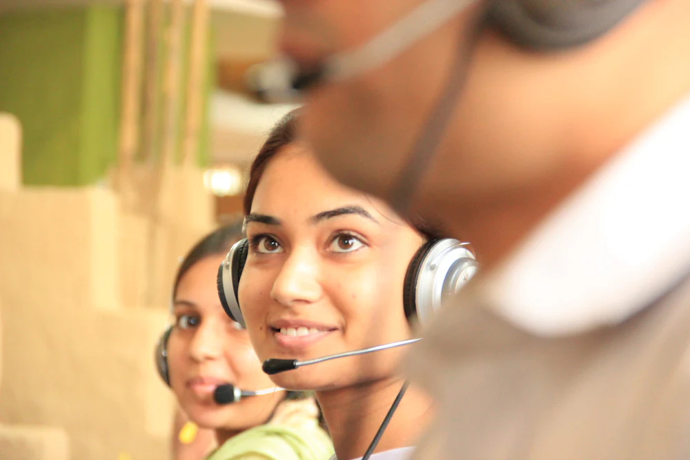 Two agents wearing headsets, smiling during a call